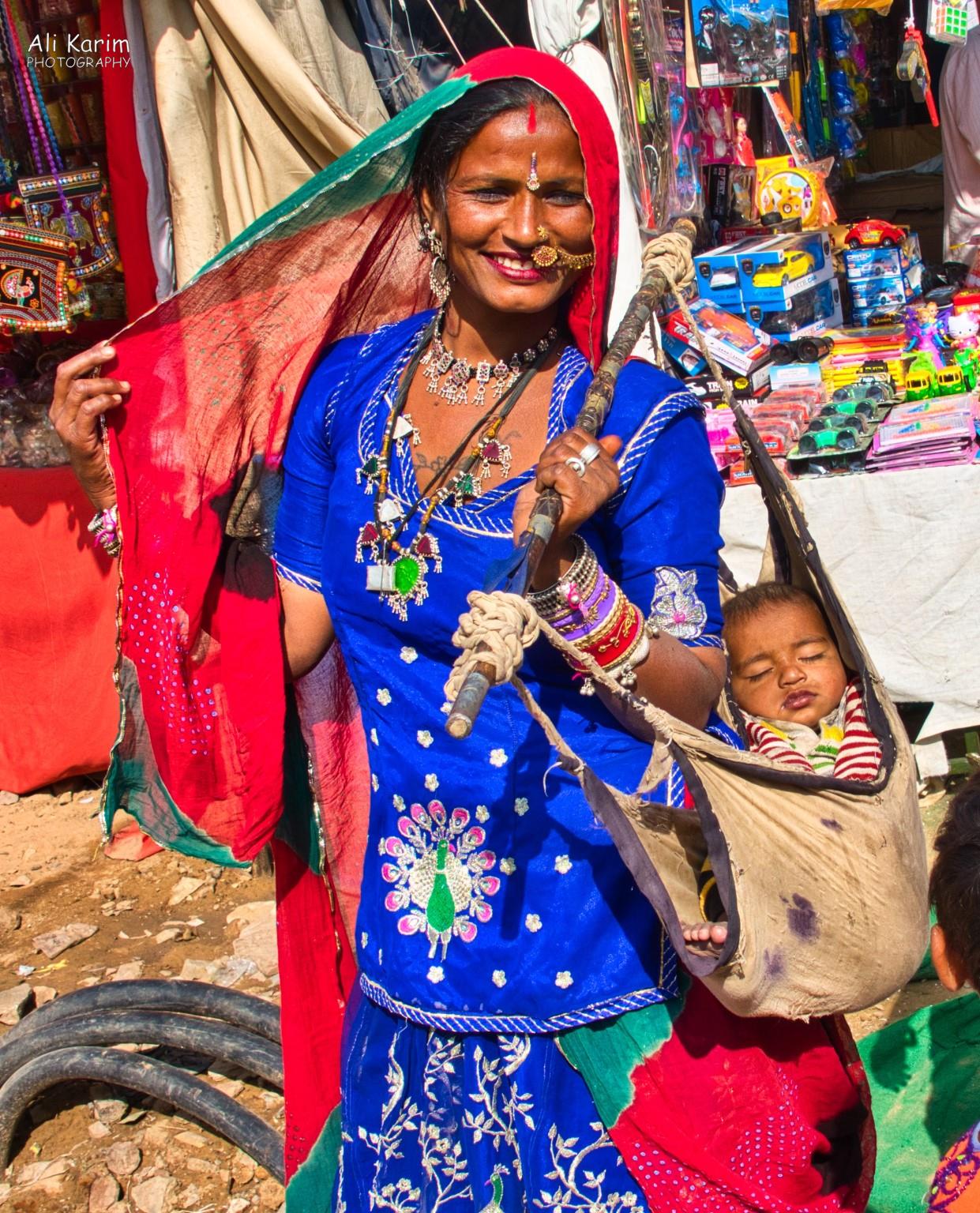 Tribal woman with her baby; interesting way to carry a baby around Pushkar, Rajasthan Tribal woman with her baby; interesting way to carry a baby around