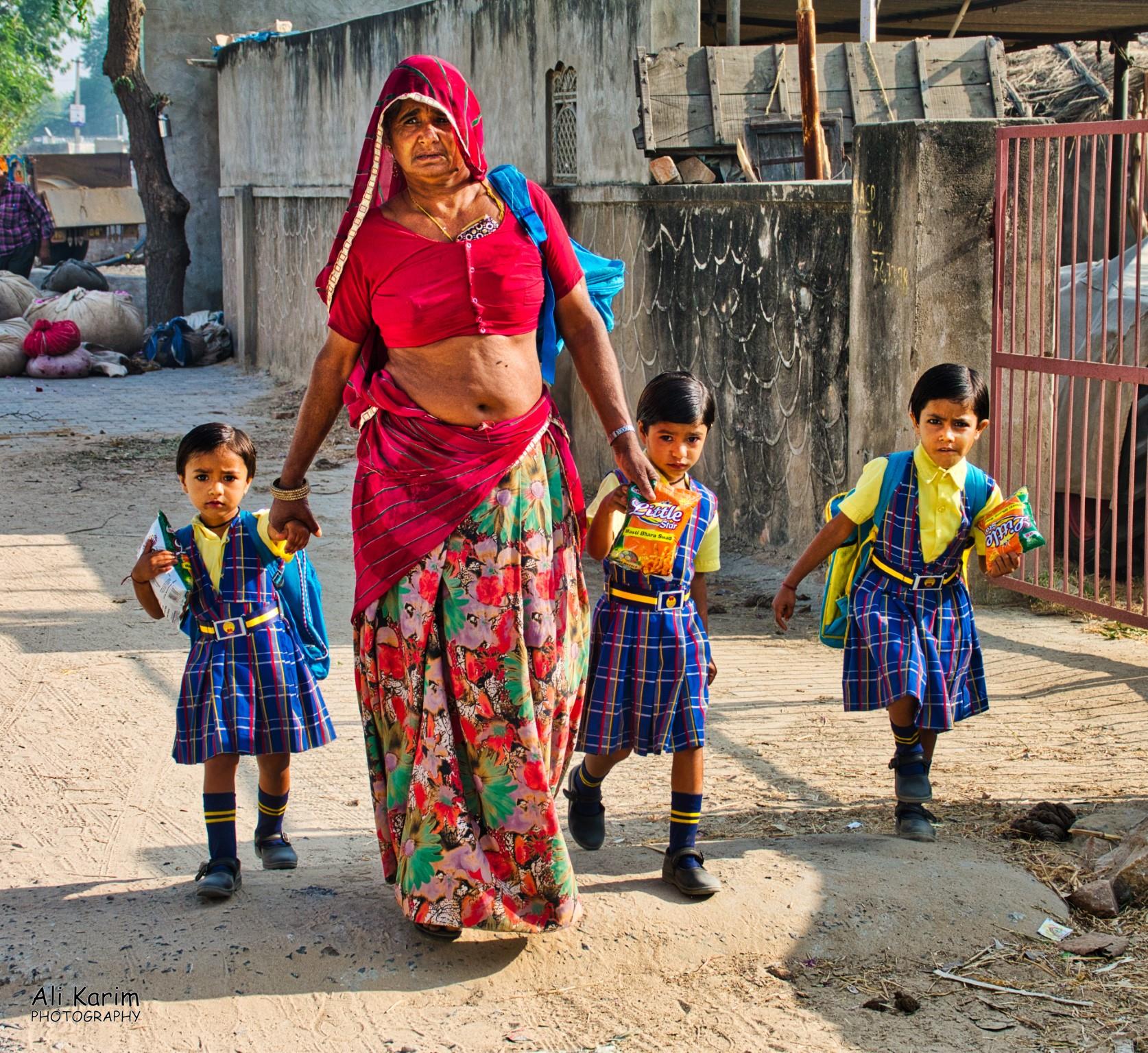 Young ladies off to school with grandma, complete with school uniform, backpack, and a bag of chips Pushkar, Rajasthan Young ladies off to school with grandma, complete with school uniform, backpack, and a bag of chips